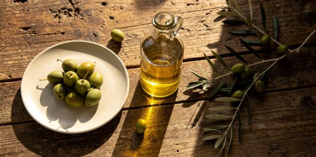Bouteille d'huile d'olive extra vierge sur une table en bois avec des olives fraîches